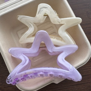 Dettaglio di fermagli per capelli a stella color crema e viola con elegante trama marmorea