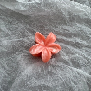 Close-up of pink marble texture frangipani flower hair claw with acrylic finish
