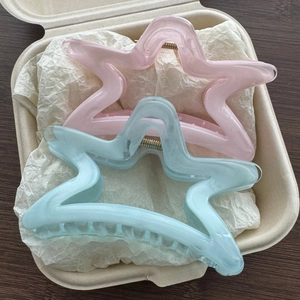 Dettaglio di due fermagli per capelli a stella traslucidi in resina rosa e blu