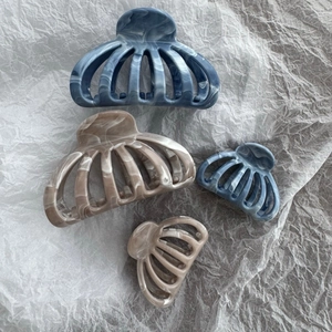 Flat lay of marble texture shark hair claws in grey and blue tones on white paper