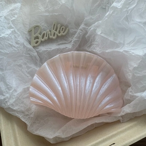 Detail of seashell hair claw in pearlescent pink with textured shell ribbing
