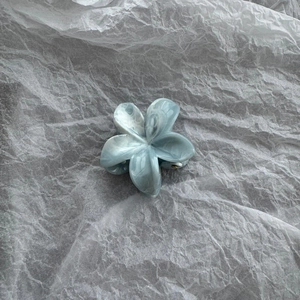 Detailed top view of light blue marble textured flower hair claw clip on white paper