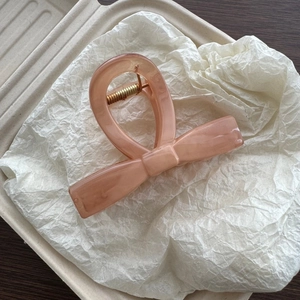 Detail view of peach marble textured ribbon hair claw clip with golden metal spring