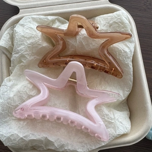 Dettaglio di fermagli per capelli a forma di stella in resina ambra e rosa con molla oro