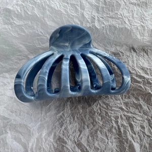 Macro detail of fan-shaped hair claw clip with blue and white marble ink patterns