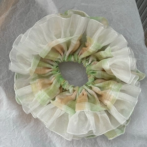 Detail of a large tiered plaid scrunchie made of sheer pastel green organza fabric