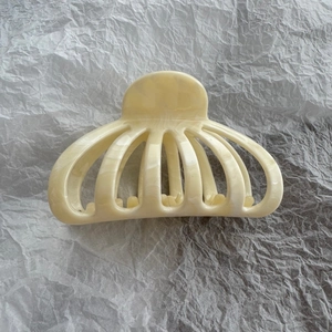 Detail of cream marble pattern hair claw clip with cutout scallop design on white background
