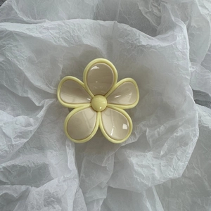 Close-up of a cream and yellow flower hair claw clip with a matte finish on white paper