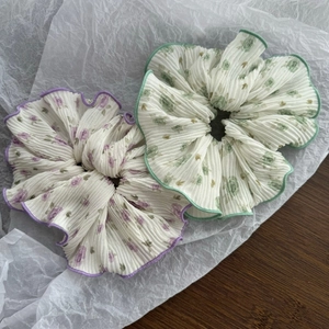 Detail of large pleated floral scrunchies in purple and green chiffon fabric texture