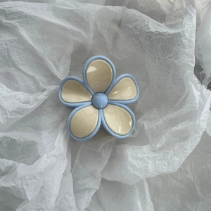 Detail of flower hair claw clip in light blue and cream white with high-gloss finish