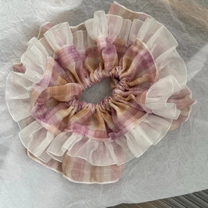 Detail of a plaid hair scrunchie with pink-purple checkered pattern and organza ruffle trim