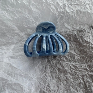 Detail view of a blue marble texture hair claw clip with a fan-shaped hollow design