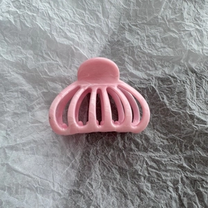 Detail of pink marble textured hair claw clip on white wrinkled paper background