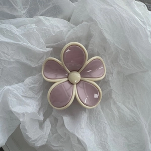 Close-up of a purple and beige flower-shaped resin hair claw clip on a white background
