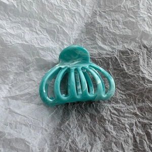 Detail of marble pattern on teal shark hair claw clip over a silver paper background
