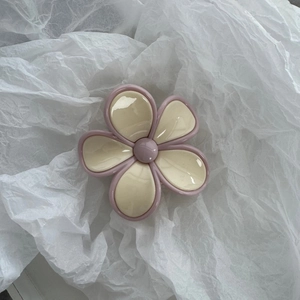 Detail of flower hair claw clip with creamy white petals and pink edges on soft paper