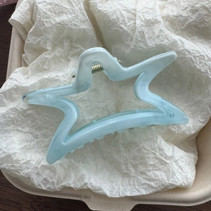 Dettaglio molletta per capelli a stella azzurra in acetato con texture a onde marine