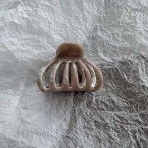 Close-up of brown marble pattern hair claw clip with a hollow fan-shaped design