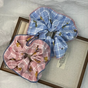 Dettaglio di elastici scrunchie a quadretti blu e rosa con motivi di cani nel vassoio