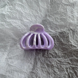 Detailed macro view of purple marble pattern hollow hair claw clip on grey textured paper