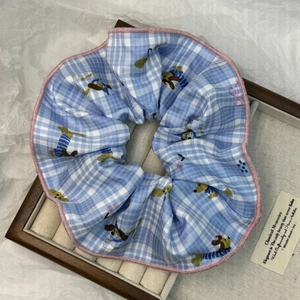 Dettaglio scrunchie a scacchi blu con motivo a cagnolino e bordi rosa cuciti