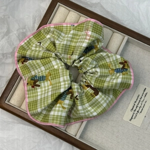 Dettaglio dell'elastico scrunchie a scacchi verdi con stampe di bassotti in scatola