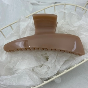 Detail view of light brown acrylic hair claw clip placed in a white decorative basket