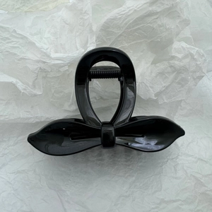 Vue détaillée d'une pince à cheveux noire brillante avec un design en nœud