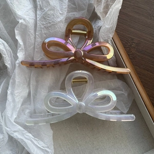 Iridescent butterfly hair claws in amber and white finish on a wooden tray