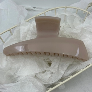 Close-up of a light brown acrylic hair claw clip with a glossy finish and non-slip teeth