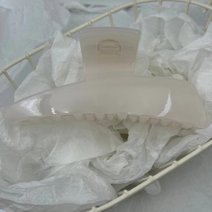 Detailed close-up of cream acrylic hair claw clip with metal spring and anti-slip teeth