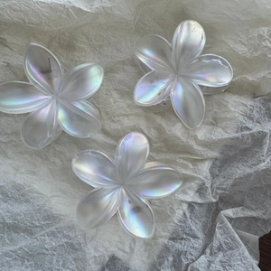 Detail of iridescent plumeria hair claws showing pearlescent texture and floral shapes