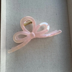 Detail of light pink mermaid bow hair claw clip with pearlescent finish and gold spring