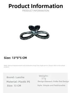 Macro view of a large black hair claw clip with white polka dots and infinity bow design