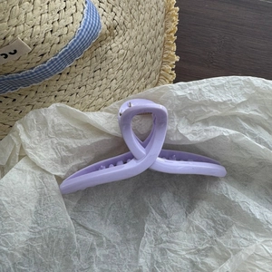 Detail of a matte purple crossover hair claw clip on a stylish summer straw hat background