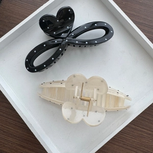 Black polka dot heart and cream butterfly hair claws in a minimalist tray