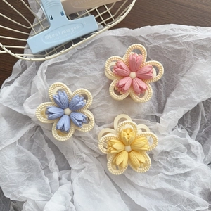 Three matte tulip flower hair claws in pastel pink, blue and yellow on white fabric