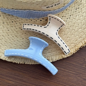 Elegant Aurora Blue and off-white hair claws with stitching detail on straw hat