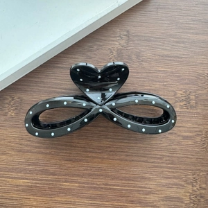 Detailed top view of black polka dot hair claw clip with heart and infinity design