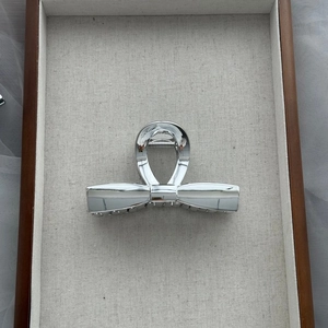 Minimalist silver acrylic bow hair claw clip for women featuring a mirror finish metal shine