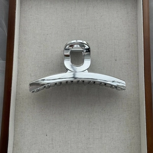 Detailed close-up of a silver semi-arc hair claw clip with a sleek metallic finish