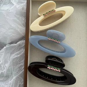 Close-up of cherry rhinestone hair claws in beige, blue and brown acrylic material