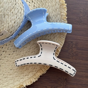 Close-up of blue and beige minimalist shark hair claws with decorative stitch detail