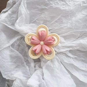 Close-up of pink tulip hair claw with matte finish and beaded white edges on soft background