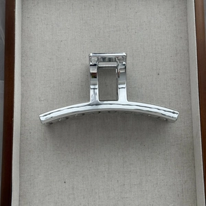 Close-up of polished silver metal shark hair claw clip with large rectangular handle
