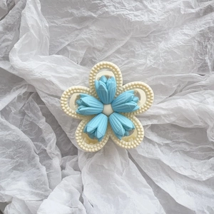 Detailed top view of a matte cream tulip flower hair claw with five blue textured petals