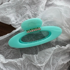 Macro detail of large mint green hair claw clip with pink rhinestone cherry patterns