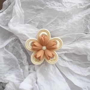 Close-up of matte tulip flower hair claw clip with orange petals on white paper background