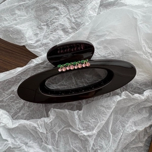 Macro detail of large cherry saturn hair claw clip with glossy finish and pink rhinestones