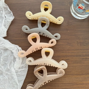 Large wave-shaped shark hair clips in five Morandi colors on a dark wooden surface